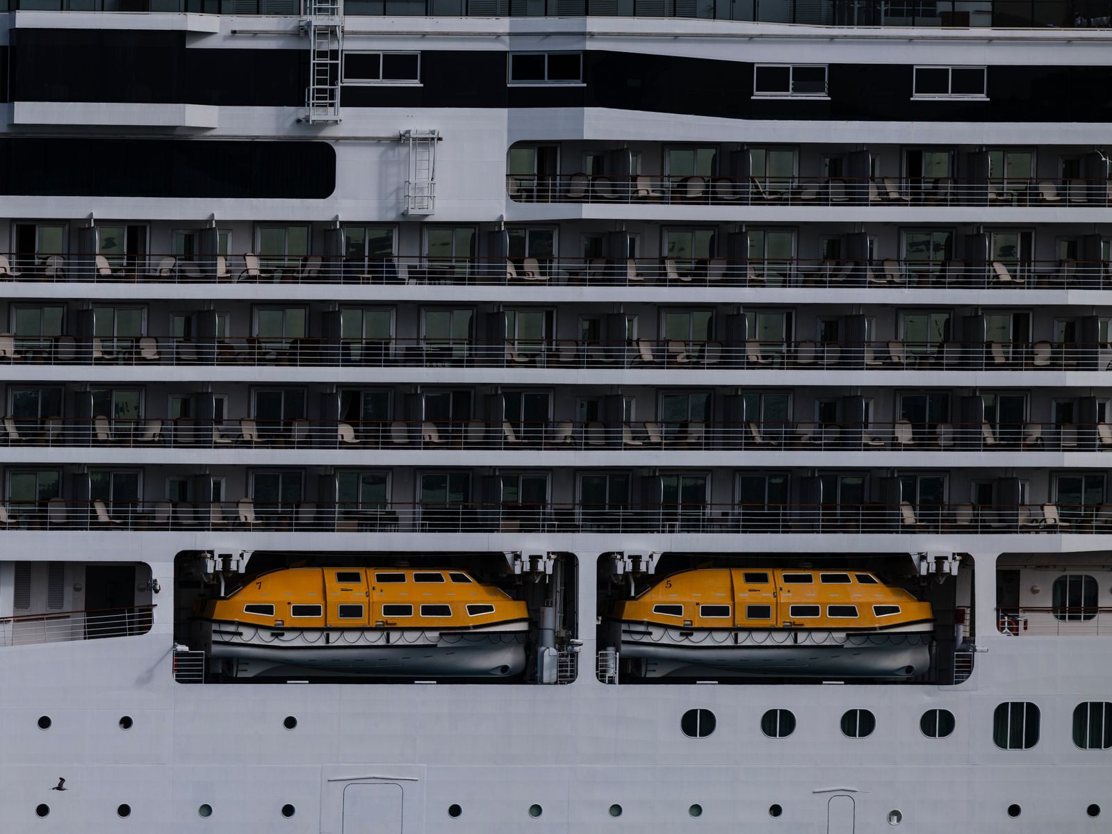 Lifeboats stowed along the side of a cruise ship, near the assembly stations used for the muster drill on a cruise