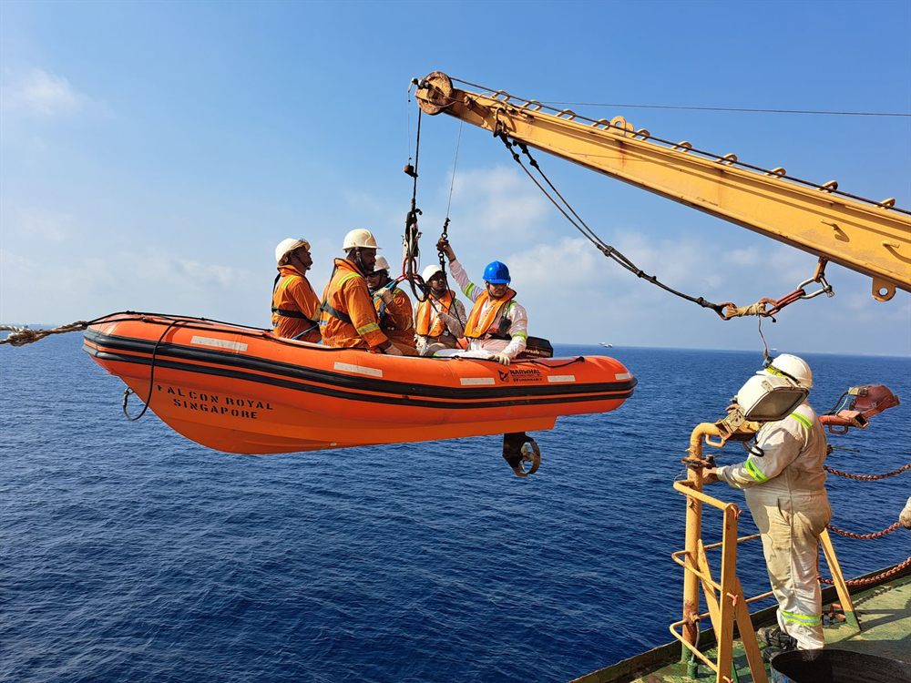 Crew in safety suits running a rescue-boat drill at sea